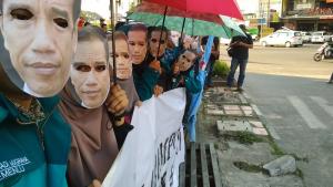 Mahasiswa Universitas Pendidikan Indonesia (UPI) menunggu Presiden Joko Widodo di depan pintu gerbang Bandara Husein Sastranegara Bandung, Jawa Barat, Sabtu (26/8). Mereka memakai topeng berwajah Jokowi, sebagai protes kebijakan impor yang dilakukan pemerintah Indonesia. Foto: Dokumentasi Aktual.com.
